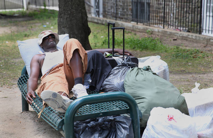 A homeless man rests on a bench in a park outside St. Vincent de Paul Church in downtown Baltimore. (CNS photo/Bob Roller) 
