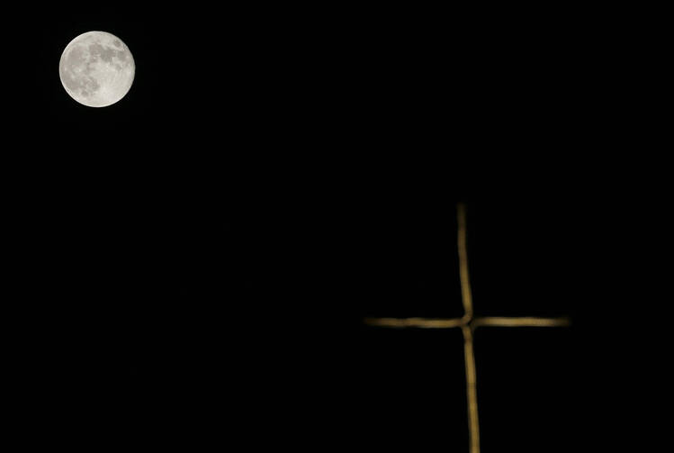 A supermoon is seen above a cross on a church in Jerusalem Sept. 9 (CNS photo/Ammar Awad, Reuters).