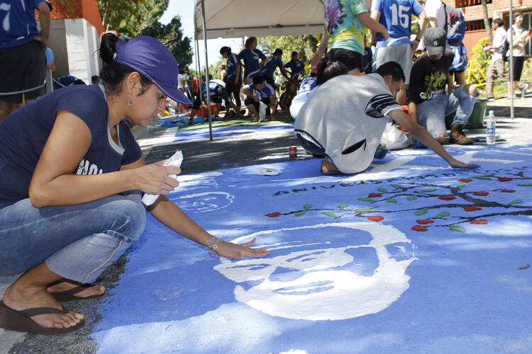 Ivette Escobar, a student at Central American University in San Salvador, helps finish a rug in honor of the victims in the 1989 murder of six Jesuits, their housekeeper and her daughter on the UCA campus, part of the 25th anniversary commemoration of the Jesuit martyrs in 2014. (CNS photo/Edgardo Ayala) 