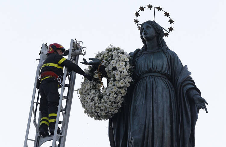 A firefighter places a wreath at the foot of a tall statue of Mary overlooking the Spanish Steps in Rome Dec. 8, the feast of the Immaculate Conception. Rome's firefighters have observed the tradition every year since 1857. (CNS photo/Paul Haring)