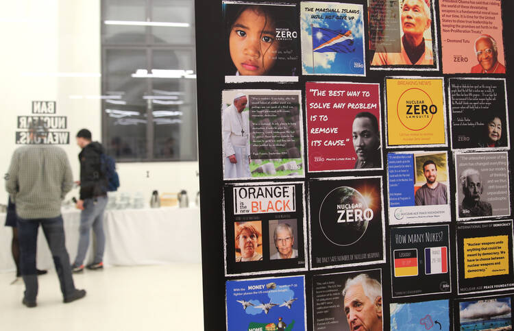 No-nukes forum participants talk at Vienna event with image of Pope Francis posted in background.