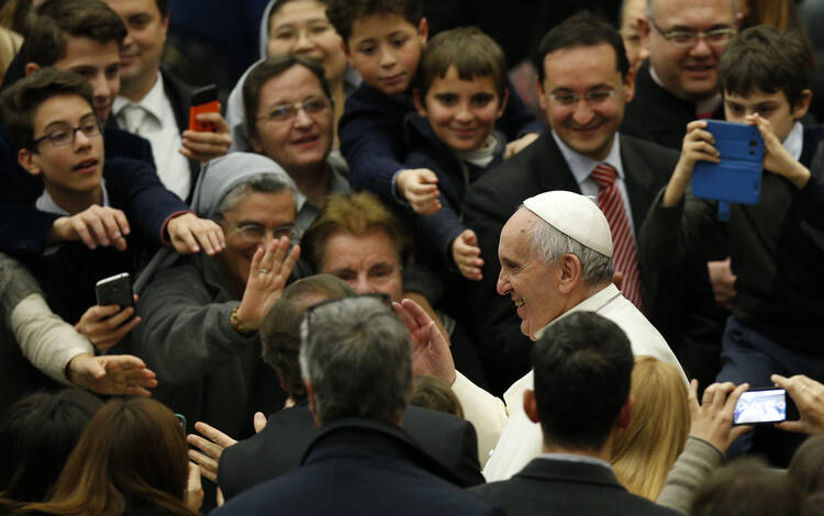 Pope Francis greets people as he leaves audience to give Christmas greetings to Vatican employees.