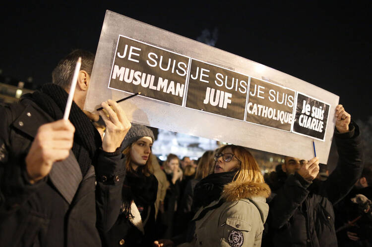 People hold a placard at vigil for Paris shooting victims.