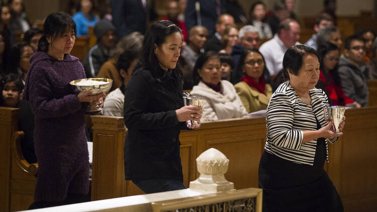 Human trafficking survivors carry offertory gifts to altar at during Mass at national shrine.