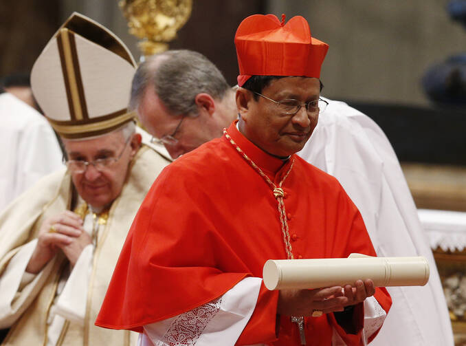 New Cardinal Charles Bo of Yangon, Myanmar, carries his scroll after receiving his red biretta from Pope Francis during a consistory at which the pope created 20 new cardinals in St. Peter's Basilica at the Vatican Feb. 14. (CNS photo/Paul Haring)