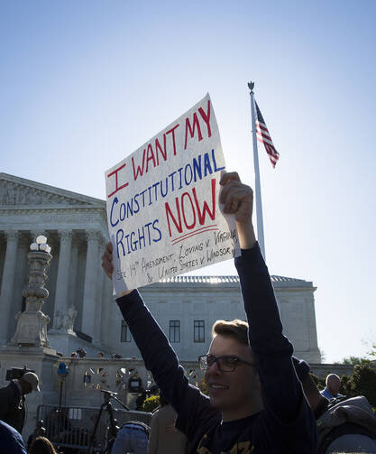 A supporter for same-sex marriage stands outside the U.S. Supreme Court in Washington April 28. The high court began hearing cases for same-sex marriages in states that bar the union. (CNS photo/Tyler Orsburn) 