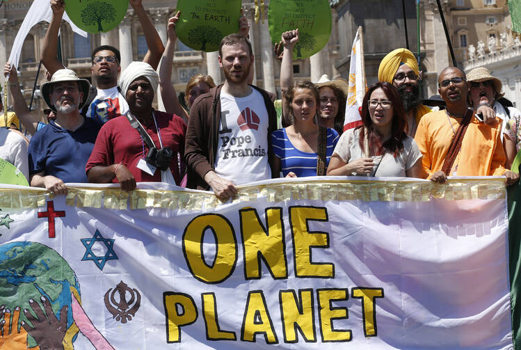 Environmental activists hold a banner as they pose for photos after attending Pope Francis' Angelus at the Vatican June 28. Some 1,500 people marched to the Vatican in support of Pope Francis' recent encyclical on the environment. (CNS photo/Paul Haring)