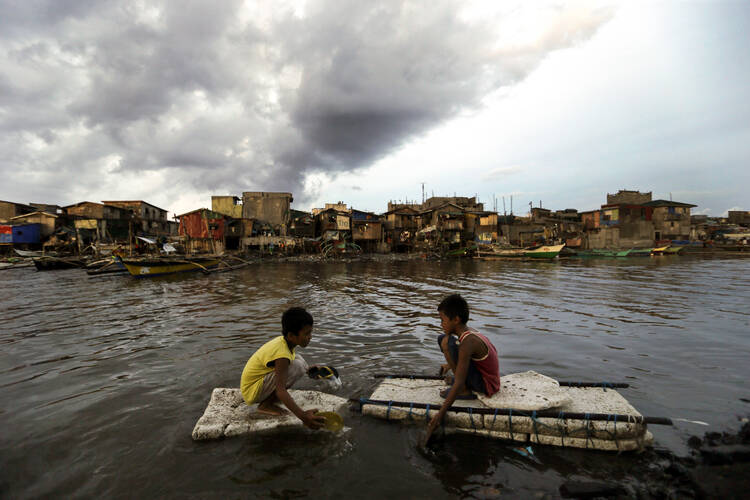 Children paddle in water in Navotas City, Philippines. (CNS photo/Ritchie B. Tongo, EPA) 