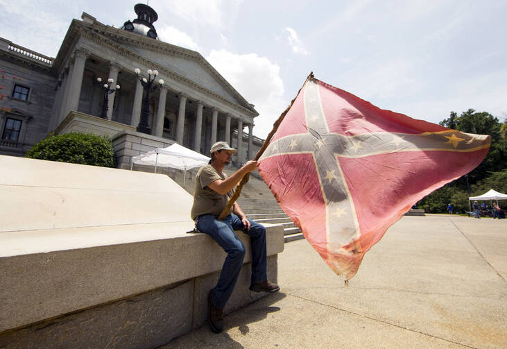 A man holds a Confederate flag outside the Statehouse in Columbia, S.C., on July 9, 2015, hours before Gov. Nikki Haley signed a bill to remove the flag from Statehouse grounds. (CNS photo/Jason Miczek, Reuters)