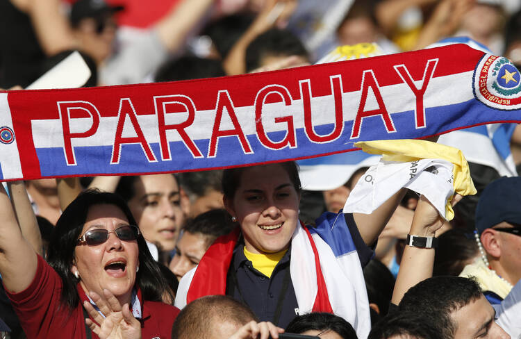 Woman holds a banner with Paraguay's national colors before Pope Francis' arrival to celebrate Mass in Nu Guazu Park in Asuncion, Paraguay, July 12. (CNS photo/Paul Haring) 