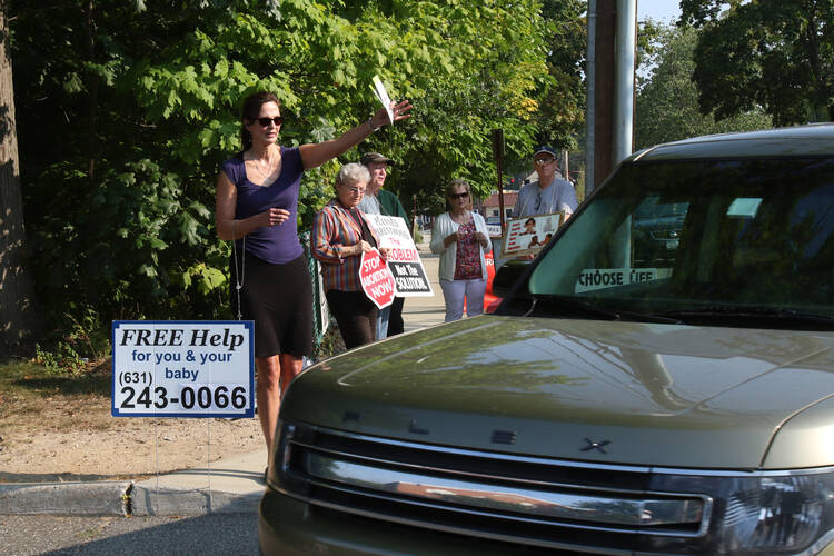 Pro-life advocate Marie Baron of St. Anthony of Padua Parish in East Northport, N.Y., tries to get a driver's attention Sept. 2 as a car enters the parking lot of a Planned Parenthood clinic in Smithtown, N.Y. (CNS photo/Gregory A. Shemitz)