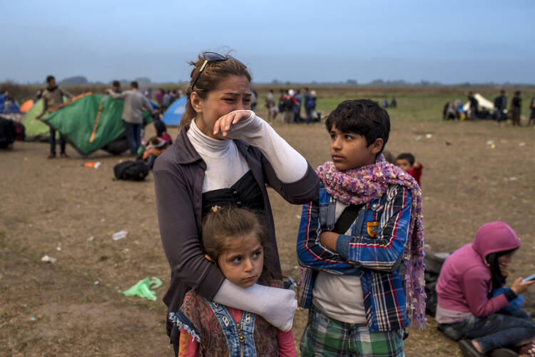 A migrant from Syria cries as she stands with her children on a field after crossing into Hungary from the border with Serbia near the village of Roszke Sept. 5. (CNS photo/Marko Djurica, Reuters) 