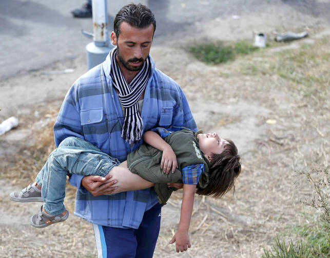 A migrant seeks medical attention for a child suffering with heatstroke in the village of Roszke, Hungary, Sept. 7. (CNS photo/Laszlo Balogh, Reuters) 