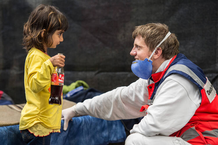 A volunteer from the German Red Cross plays with a migrant girl from Syria in an emergency shelter in Rottenburg Sept. 16. "Do not abandon victims" of conflicts in Syria and Iraq, Pope Francis pleads. (CNS photo/Wolfram Kastli, EPA) 