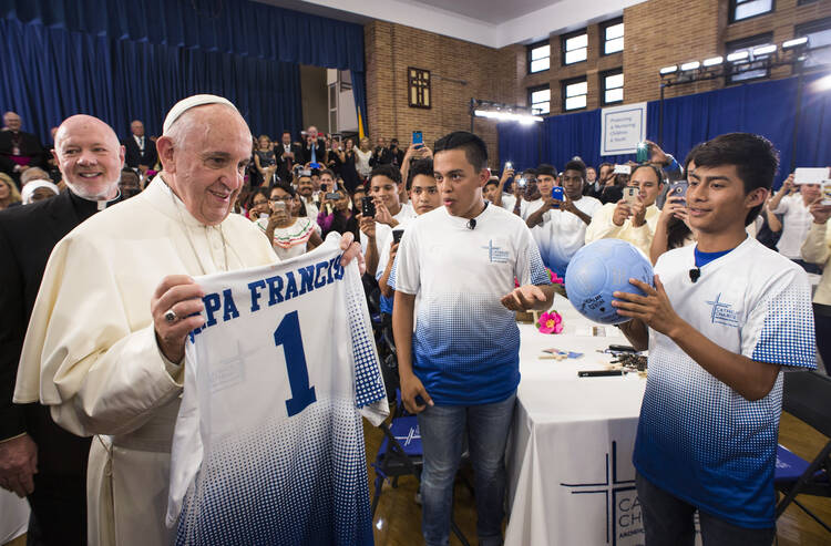 Pope Francis receives a Catholic Charities jersey and an autographed soccer ball during his meeting with immigrant families at Our Lady Queen of Angels School in the East Harlem area of New York in September 2015. (CNS photo)