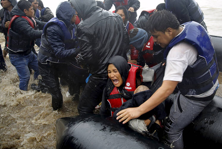 Afghan mother holds her baby as she struggles to disembark raft during a rainstorm in Lesbos, Greece, Oct. 23. Members of Congress were told in Washington that Europe's refugee crisis demands global response. (CNS photo/Yannis Behrakis, Reuters)