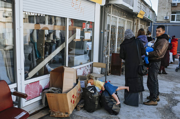 An internally displaced Ukrainian family stands in line as they wait for humanitarian aid at a distribution center in Kiev, Ukraine, in October. (CNS photo/Roman Pilipey, EPA)