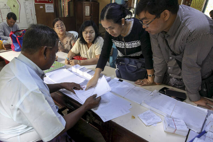 A staff member of a polling station assists people to check their names on final voter list during early voting in Mandalay, Myanmar, Nov. 1. Myanmar will hold its nationwide general elections Nov. 8. (CNS photo/Hein Htet, EPA) 