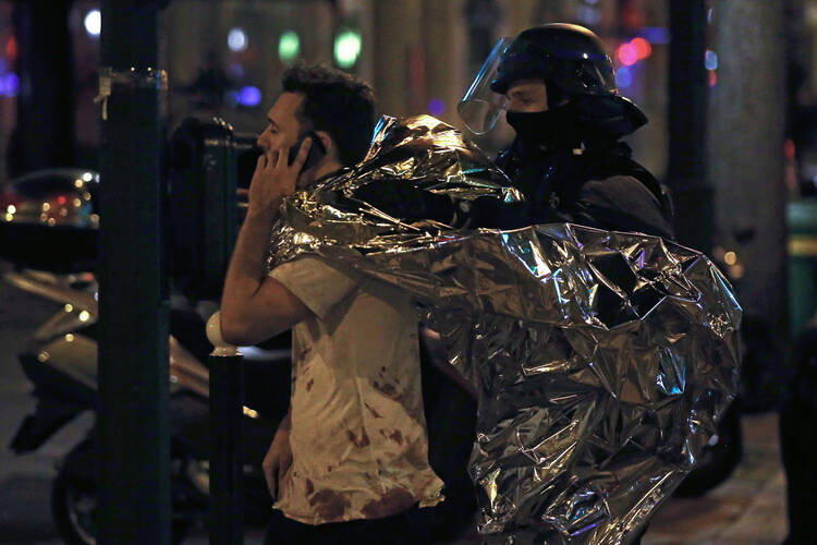 Outside the Bataclan, a survivor puts his cellphone to use. Dozens of people were killed in a series of attacks in Paris on Nov. 13. (CNS photo/Etienne Laurent, EPA) 