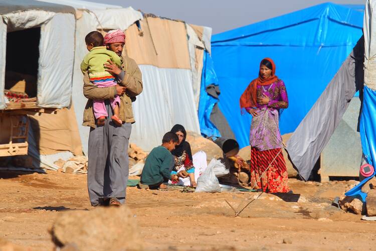 Internally displaced Syrians stand outside their tents Nov. 20 at a camp in Idlib, Syria. (CNS photo/Ammar Abdullah, Reuters) 