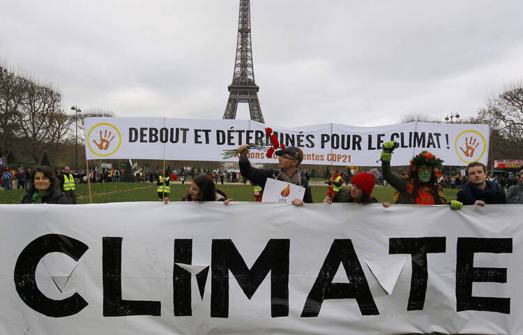 Environmentalists hold a banner that reads, "Standing and Determined for the Climate," during a Dec. 12 protest near the Eiffel Tower in Paris as the U.N. climate conference ended. (CNS photo/Mal Langsdon, Reuters)