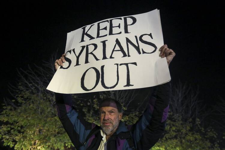 An anti-immigration protester holds up a sign as people take part in pro-immigration protest in the Manhattan borough of New York on Dec. 10. (CNS photo/Carlo Allegri, Reuters)