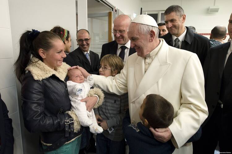 Pope Francis blesses a baby during a visit to a Caritas center for the homeless near the Termini rail station in Rome Dec. 18. The pope opened a Door of Mercy at the center. (CNS photo/L'Osservatore Romano, handout)