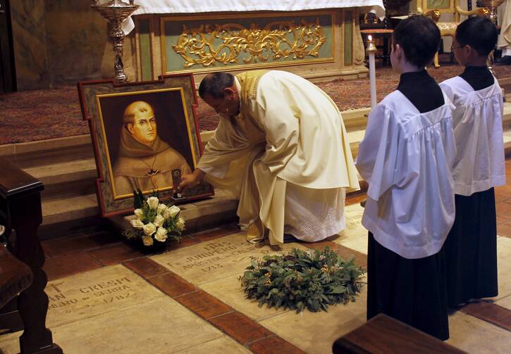 Father Miguel Rodriguez sets a relic on the tomb of St. Junipero Serra during Mass at the Carmel Mission Basilica in Carmel, Calif., Sept. 23, 2016, the day the Spanish missionary and founder of the California mission system was cannonized by Pope Francis in Washington. (CNS photo/Michael Fiala, Reuters)