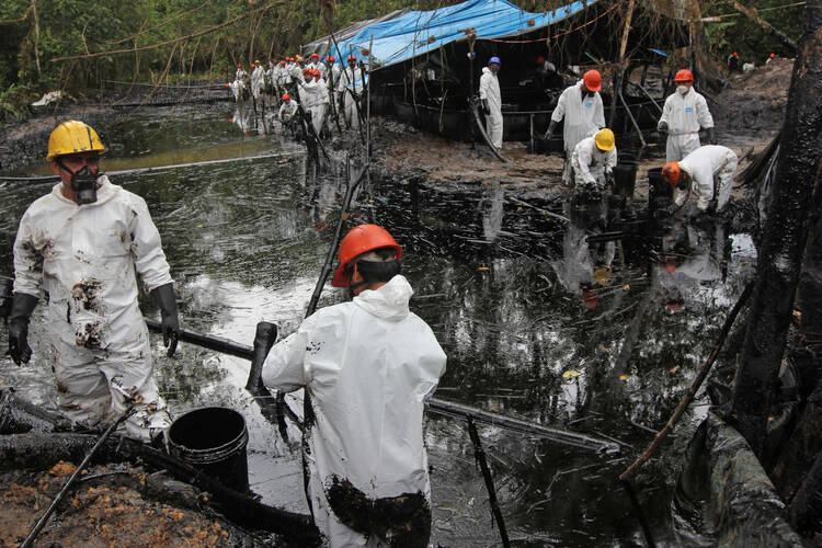 Workers collect oil from a stream below the site of a pipeline break that spilled at least 2,000 barrels of oil in northern Peru. (CNS photo/Barbara Fraser)