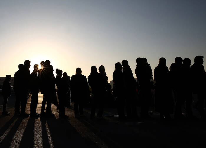 Migrants and refugees wait in a long line Feb. 25 to receive food distributed by volunteers after their arrival in Athens, Greece. (CNS photo/Simela Pantzartzi, EPA) 