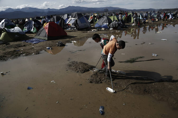 Migrant children play in water at a refugee camp in Idomeni, Greece, March 8. (CNS photo/Yannis Kolesidis, EPA) 