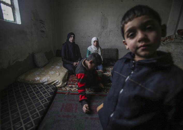 A child poses for a photo with his family in Al-Qaboon, Syria, Feb. 22. His father disappeared four years ago in the ongoing conflict. (CNS photo/Mohammed Badra, EPA)
