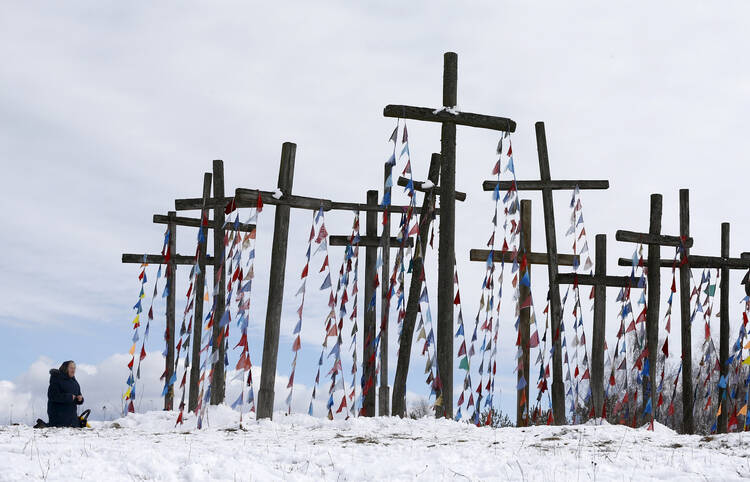 A woman prays on a hill with wooden crosses after a procession celebrating Palm Sunday in Oshmiany, Belarus, March 20. (CNS photo/Vasily Fedosenko, Reuters)