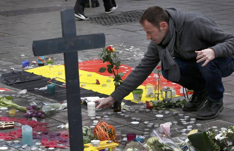 A man places flowers on a street memorial March 23 following bomb attacks in Brussels. Three nearly simultaneous attacks March 22 claimed the lives of dozens and injured more than 200. (CNS photo/Francois Lenoir, Reuters)