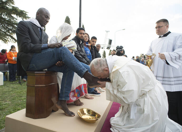 Pope Francis kisses the foot of a refugee during Holy Thursday Mass of the Lord's Supper at the Center for Asylum Seekers in Castelnuovo di Porto, about 15 miles north of Rome in March 2016. The pope washed and kissed the feet of refugees, including Muslims, Hindus and Copts. (CNS photo/L'Osservatore Romano, handout)