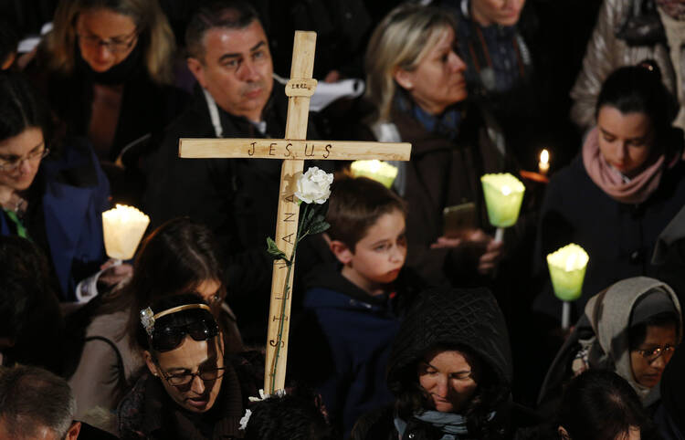 A woman holds a cross during the Way of the Cross presided at by Pope Francis outside the ancient Colosseum in Rome March 25. (CNS photo/Paul Haring)