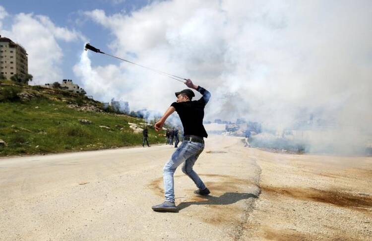 A Palestinian returns an Israeli tear gas canister during a protest marking Land Day Ramallah, West Bank, March 30. (CNS photo/Mohamad Torokman, Reuters)