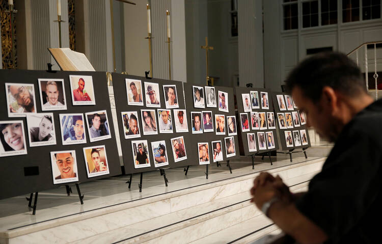 A man prays on June 15, 2016, in front of photographs of victims of the mass shooting at an L.G.B.T. nightclub in Orlando, Fla., during a vigil at a nearby church. The mass shooting was one of the hate crimes discussed on July 16 at a hearing held by the Helsinki Commission. (CNS photo/Jim Young, Reuters) 