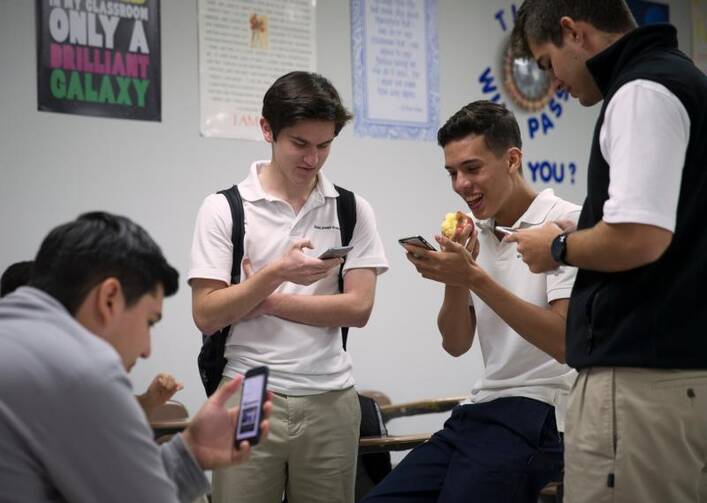 Students at St. Joseph Academy in Brownsville, Texas, check their smartphones during lunch May 3. (CNS photo/Tyler Orsburn)