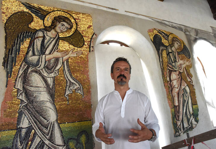 Giammarco Piacenti, CEO of the Piacenti restoration center, stands in front of angel mosaics in the Church of the Nativity July 5 in Bethlehem, West Bank. Restoration specialists from the center completed their work in June. (CNS photo/CNS/Debbie Hill)