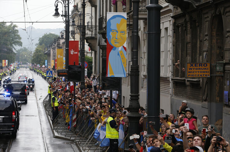 A banner showing St. John Paul II hangs from a lamp pole in Krakow, Poland, as Pope Francis arrives to attend World Youth Day in 2016. Surveys show that Poland leads Europe, and the United States, in religious commitment. (CNS photo/Paul Haring)