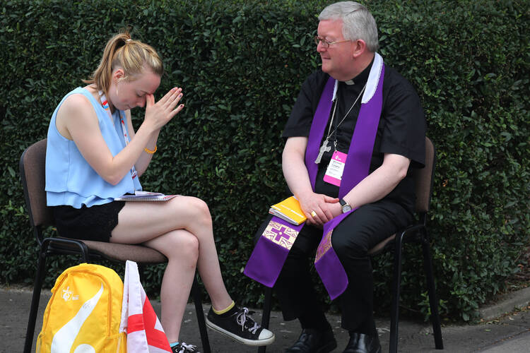 A World Youth Day pilgrim becomes emotional as a priest hears her confession at Sacred Heart Church in Krakow, Poland, July 28. (CNS photo/Bob Roller) 