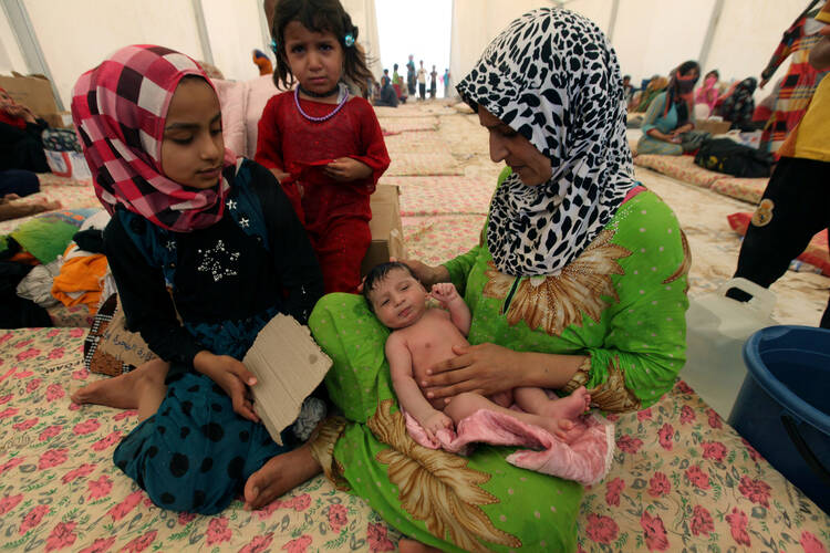 A displaced Iraqi woman carries her sleeping child July 16 at a refugee camp near Mosul, Iraq. (CNS photo/Azad Lashkari, Reuters)