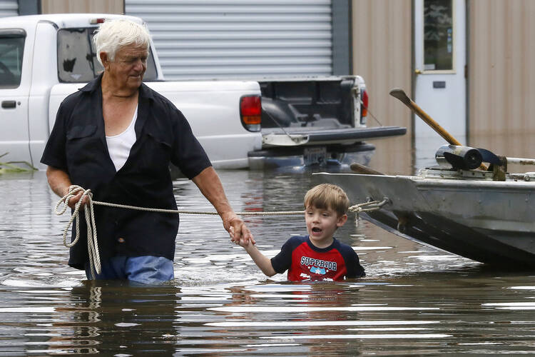 Richard Rossi and his 4-year-old great-grandson Justice wade through water Aug. 15 after their home flooded in St. Amant, La. (CNS photo/Jonathan Bachman, Reuters)