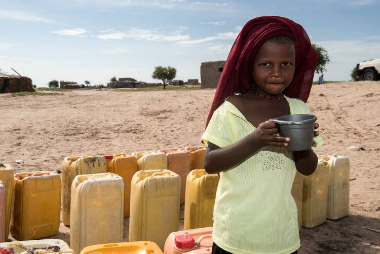 Life at a refugee camp in Kindjani, Niger, for Nigerians fleeing Boko Haram in 2016: A young girl drinks water delivered to the community by Catholic Relief Services. (CNS photo/Michael Stulman, CRS)