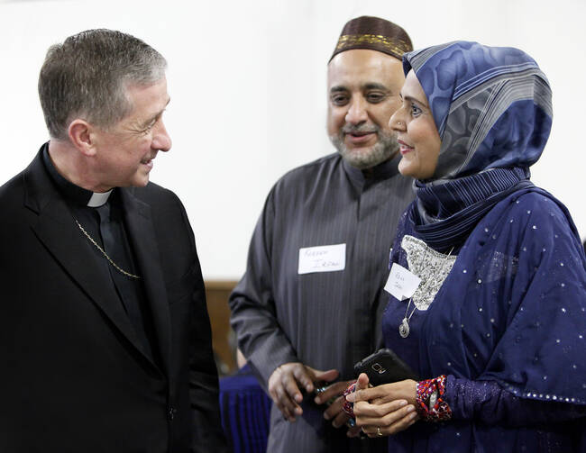 Chicago Archbishop Blase J. Cupich visits with a couple during a June 27 Catholic-Muslim dinner in Bridgeview, Ill. (CNS photo/Karen Callaway/Catholic New World)