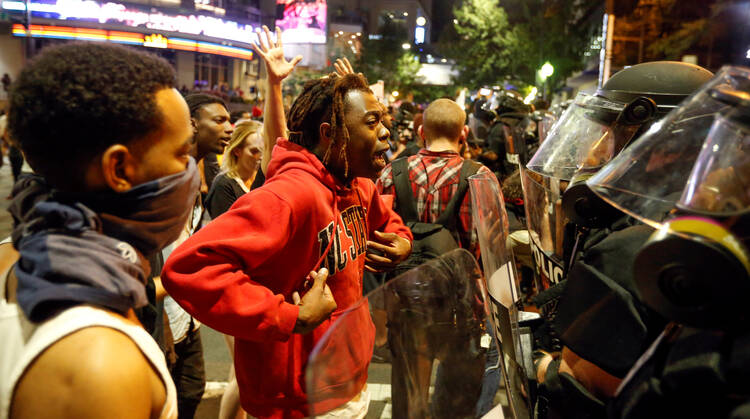 A man confronts riot police during Sept. 21 protests in Charlotte, N.C., after police fatally shot Keith Lamont Scott in the parking lot of an apartment complex. (CNS photo/Jason Miczek, Reuters)