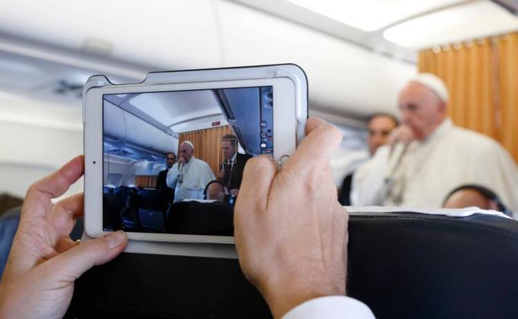 A journalist uses a tablet to photograph Pope Francis as he answers questions from journalists aboard his flight from Malmo, Sweden, to Rome Nov. 1. (CNS photo/Paul Haring) 
