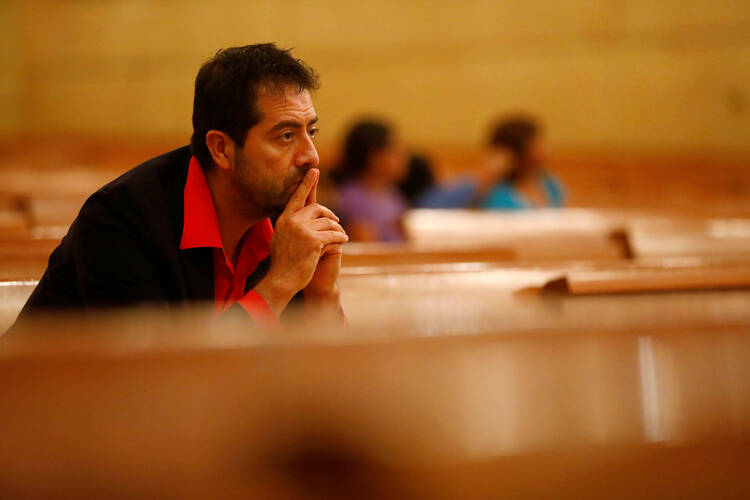 Ernesto Vega listens as Archbishop Jose H. Gomez leads an interfaith prayer service for the immigrant community in November at the Cathedral of Our Lady of the Angels in Los Angeles. (CNS photo/Patrick T. Fallon, Reuters) 