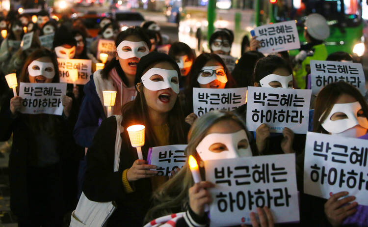 South Korean university students carry candles and placards that read "Park Geun-Hye Step Down" Nov. 15 in Seoul. The South Korean president is embroiled in scandal involving a longtime friend. (CNS photo/Yang Ji-Woong, EPA) 
